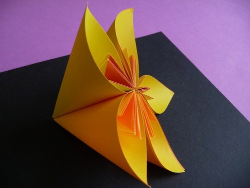 13. Apply glue or double sided tape along one of the outside edges. Press against the edge of another petal, making sure the top and bottom are properly aligned. Continue until all five petals are attached. If you decide to make a kusudama flower, you will need to make 12 more of these smaller flowers.